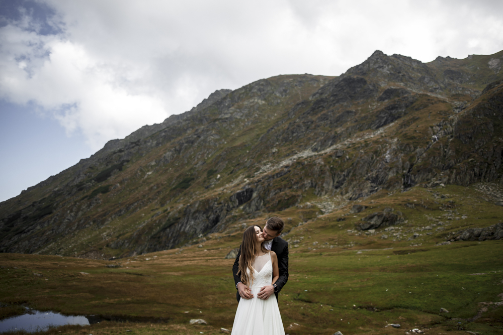 Young caucasian married couple embracing against mountains while