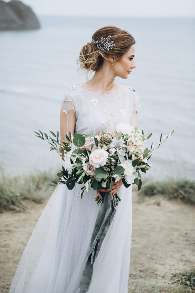 Pretty bride with wedding flowers by the sea